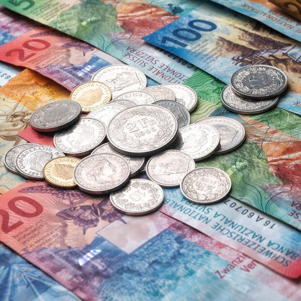 Schweizer Banknoten mit darüberliegendem Kleingeld